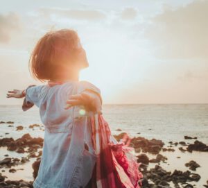 Frau mit Blick aufs Meer im Sonnenschein von fuu-j in Unsplash