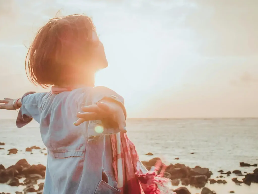Frau mit Blick aufs Meer im Sonnenschein von fuu-j in Unsplash